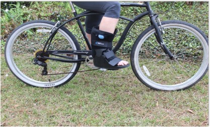 Colene's foot in her walking boot cast as she sits astride her bike on the day of the teacher parade